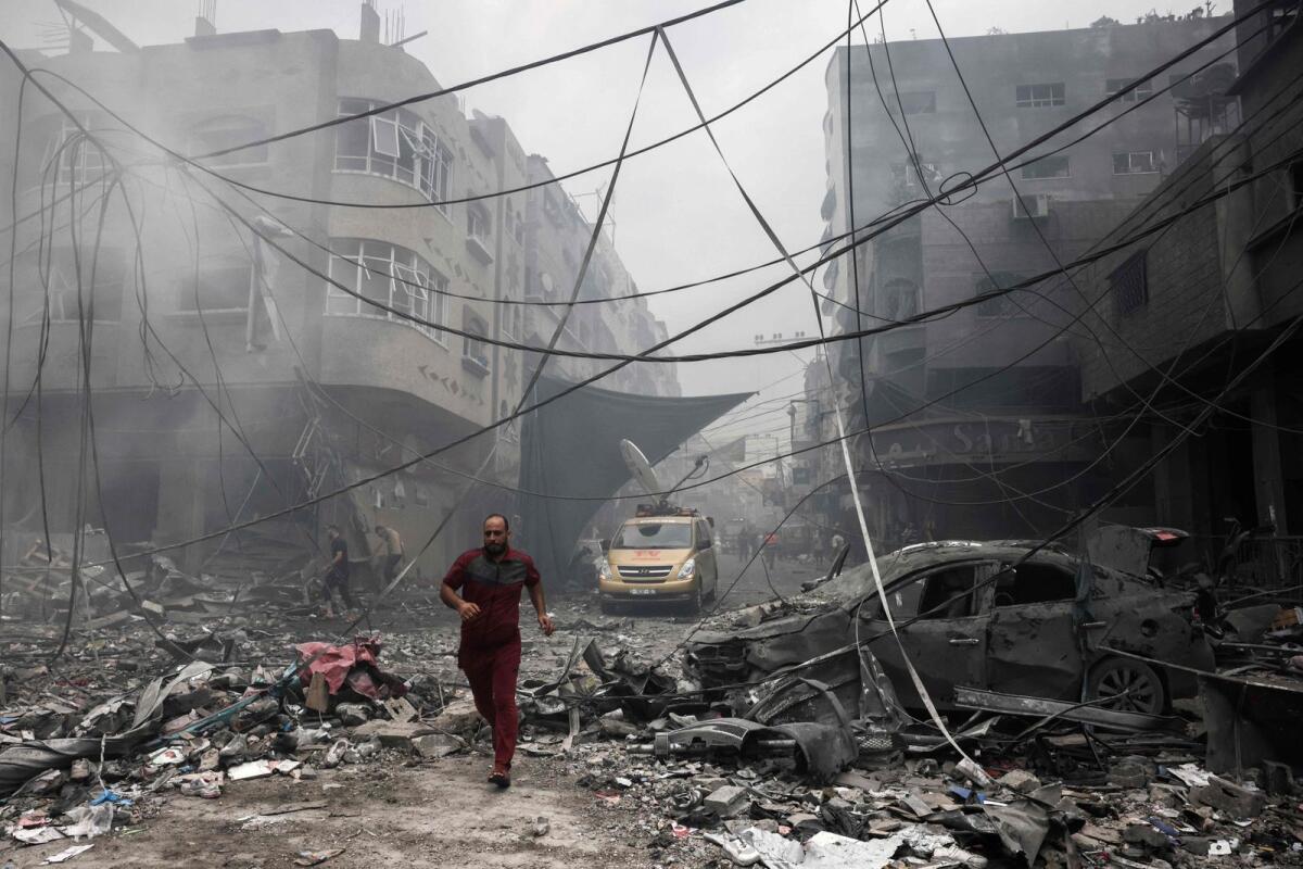 A Palestinian runs amidst the debris after an Israeli airstrike on buildings in the refugee camp of Jabalia in the Gaza Strip on October 9, 2023.Photo: AFP