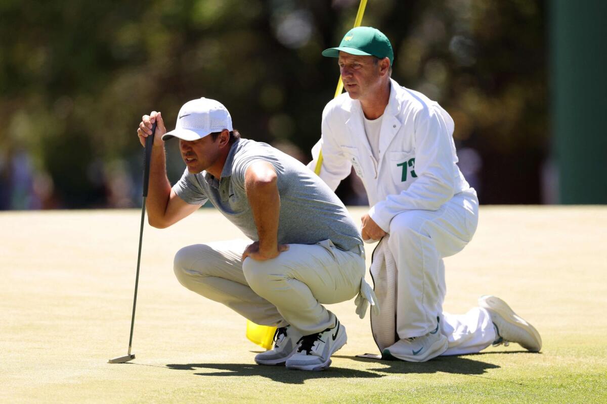 Brooks Koepka of the United States and his caddie line up a putt. - AFP
