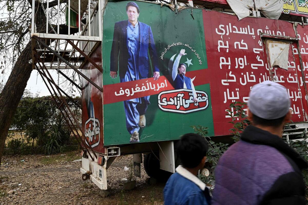 People walk past a poster of jailed Pakistan's former prime minister Imran Khan, near his party office in Islamabad on February 4, 2024. — AFP