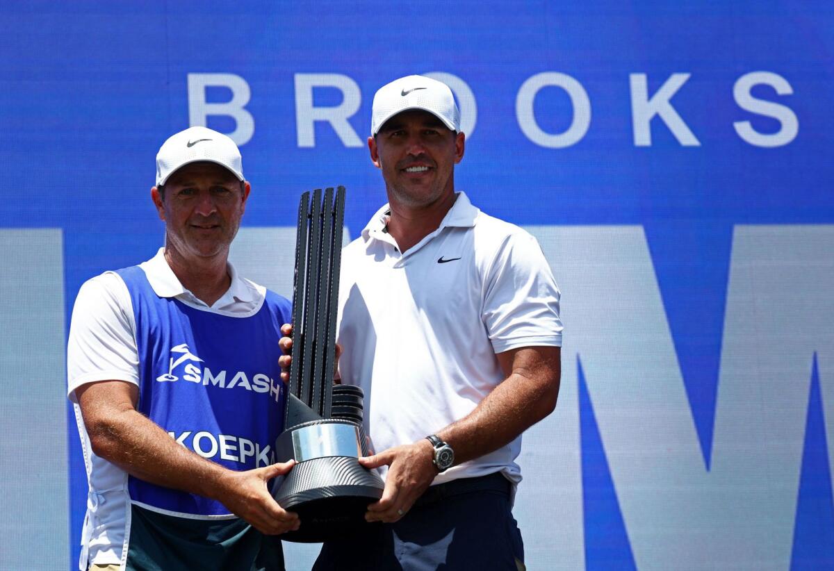 Smash GC's Brooks Koepka celebrates with his caddie and the trophy after winning the LIV Golf Singapore. - Reuters