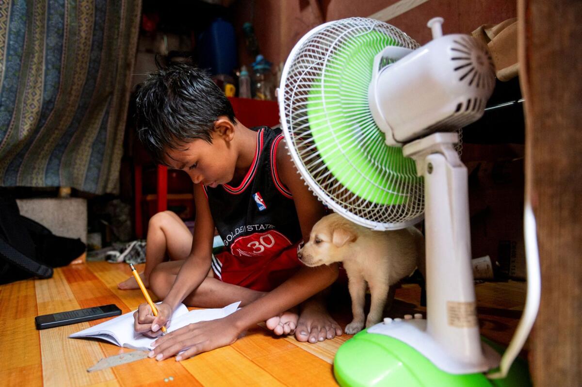 A student answers his learning module following the suspension of in-person classes, inside his house in Manila, Philippines, on April 26, 2024. — Reuters