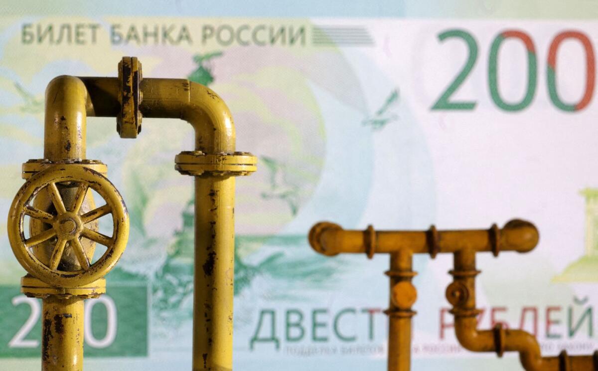 A model of a natural gas pipeline and a Russian rouble banknote. Proceeds from oil and gas sales for Russia's federal budget rose in the first half of the year to 5.698 trillion roubles ($65.12 billion).