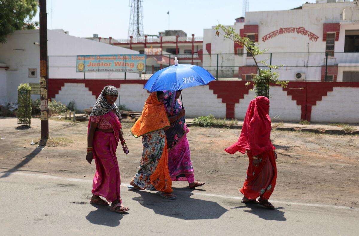 Women shelter under an umbrella due to the heat as they leave a polling station after casting their vote. Photo: Reuters