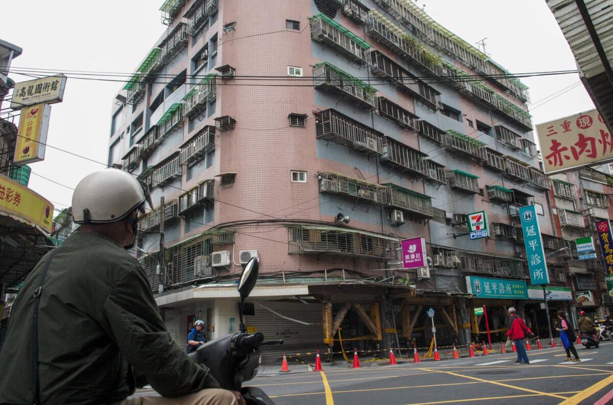 A motorcyclist looks at a tilted building caused by the April 3 magnitude-7.4 earthquake at Tucheng district in New Taipei City on April 6, 2024. Photo: AFP file