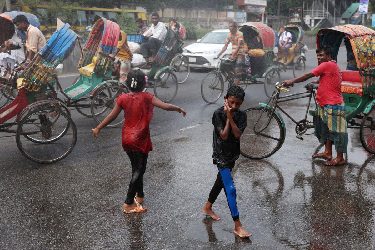 Children cool themselves in the water, sprayed from a spray cannon by Dhaka North City Corporation, during a countrywide heatwave in Dhaka, Bangladesh, on Sunday. — Reuters