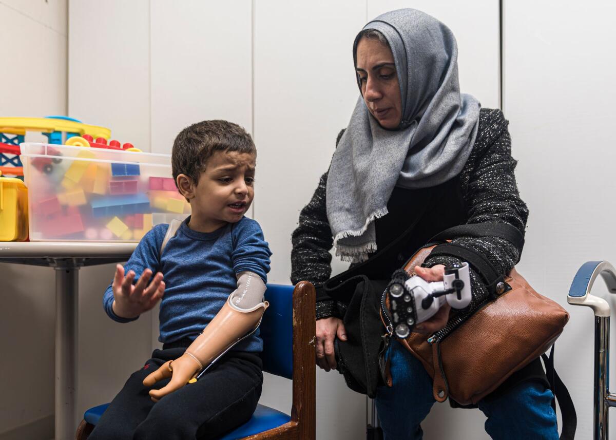 Four-year-old Omar Abu Kuwaik expresses frustration at using his new prosthetic arm with his aunt, Maha Abu Kuwaik, during an occupational therapy session at Shriners Children's Hospital on Feb. 28, 2024, in Philadelphia. — AP