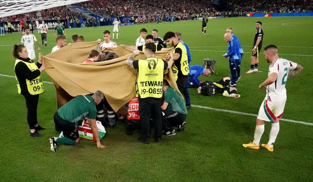 Stewards hold up sheets as Hungary's Barnabas Varga receives medical attention after sustaining an injury during the match against Scotland. — Reuters