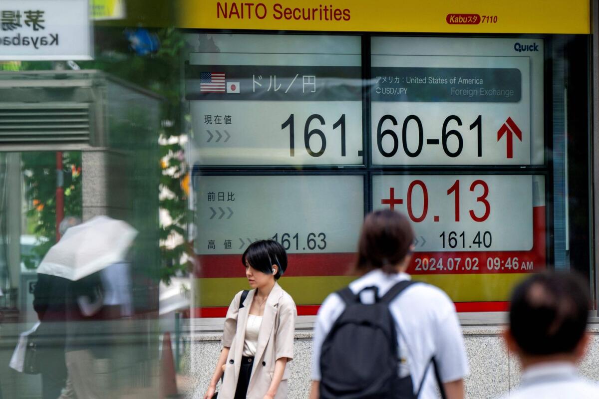 Pedestrians walk past an electronic board displaying the exchange rate for the Japanese yen against the US dollar in Tokyo on Tuesday. — AFP