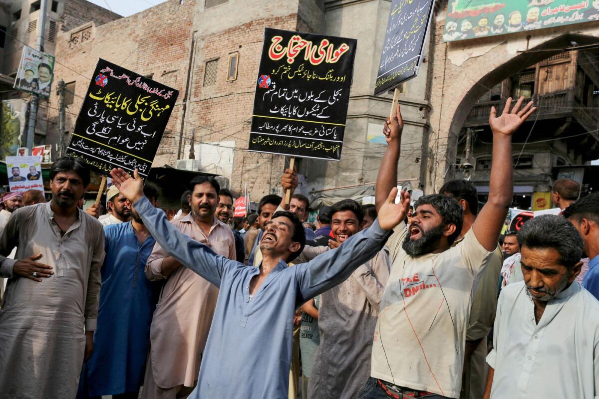 Members of trade unions hold placards and shout slogans as they demand reduction of electricity tariffs during a protest in Multan on Monday. — AFP