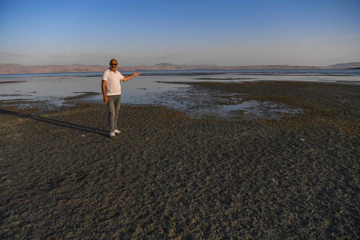A picture taken on August 17, 2023 in Van, eastern Turkey, shows local ecologist Ali Kalcik standing on a dry bank of Lake Van, where the waters have receded by around four kilometres. — AFP