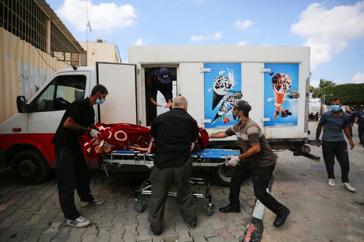 People carry the body of a Palestinian from an ice cream truck where it was kept, as the hospital morgues are packed. —  Reuters