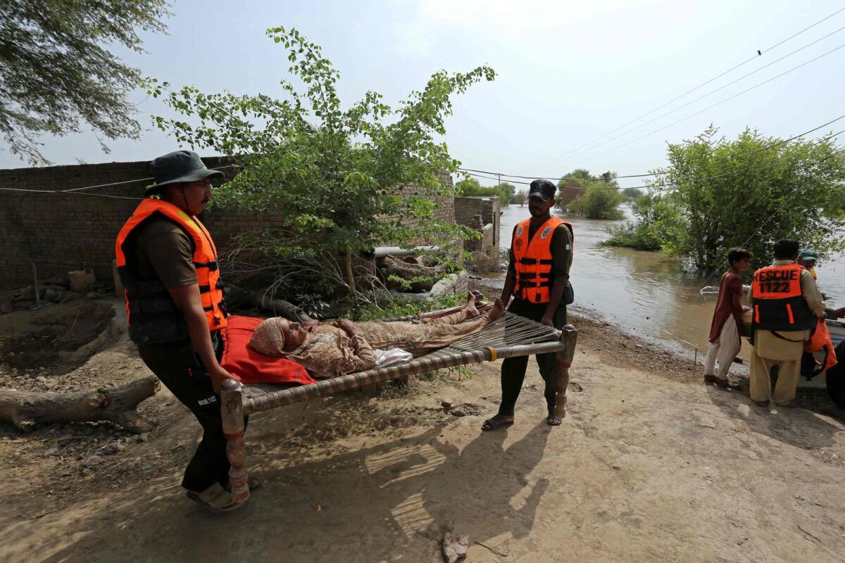 An elderly woman is being evacuated by rescue staff from a flood affected area in Bahawalnagar of Punjab province on August 26, 2023.  — AFP