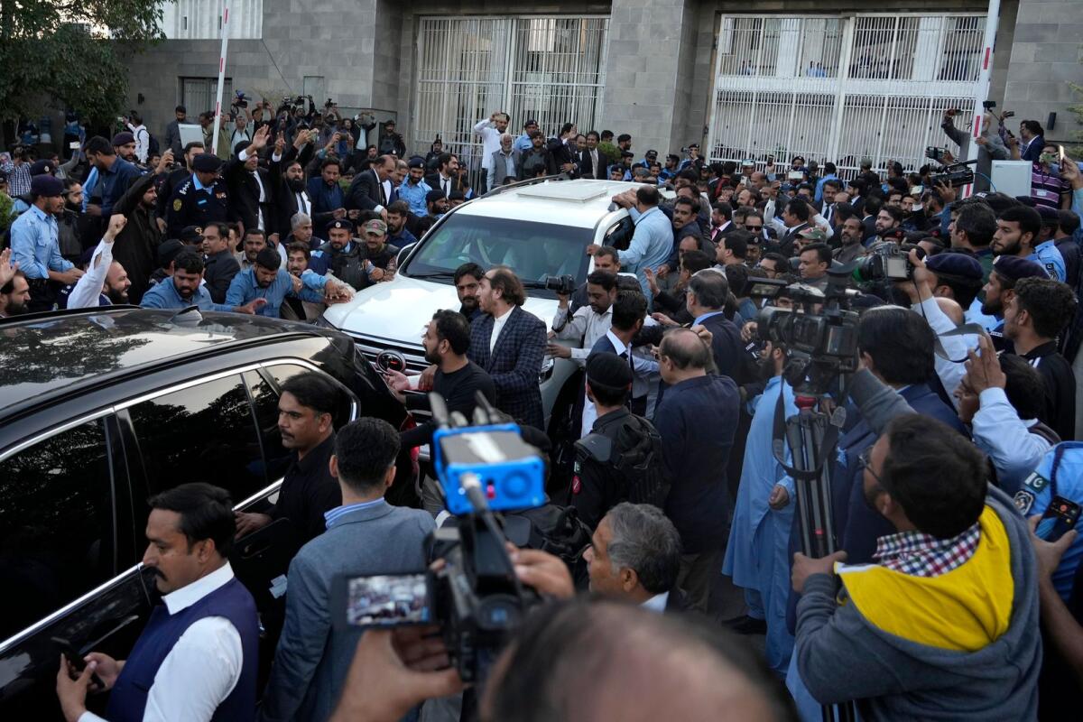 Security personnels clear way for a vehicle, centre in white, carrying Nawaz Sharif leaving after appearing in a court in Islamabad, Pakistan, on Thursday, – AP
