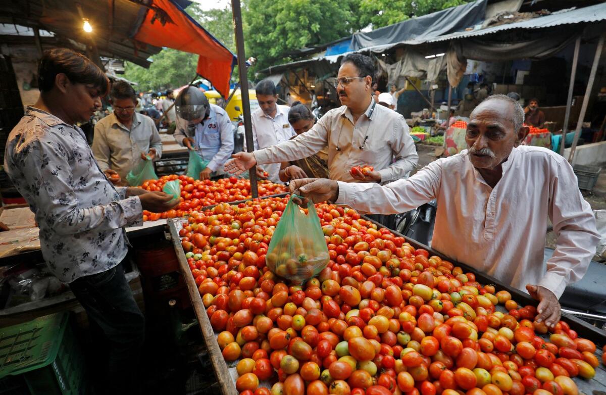 People buy tomatoes from a vendor at a vegetable market in Ahmedabad on Tuesday. Photo: Reuters