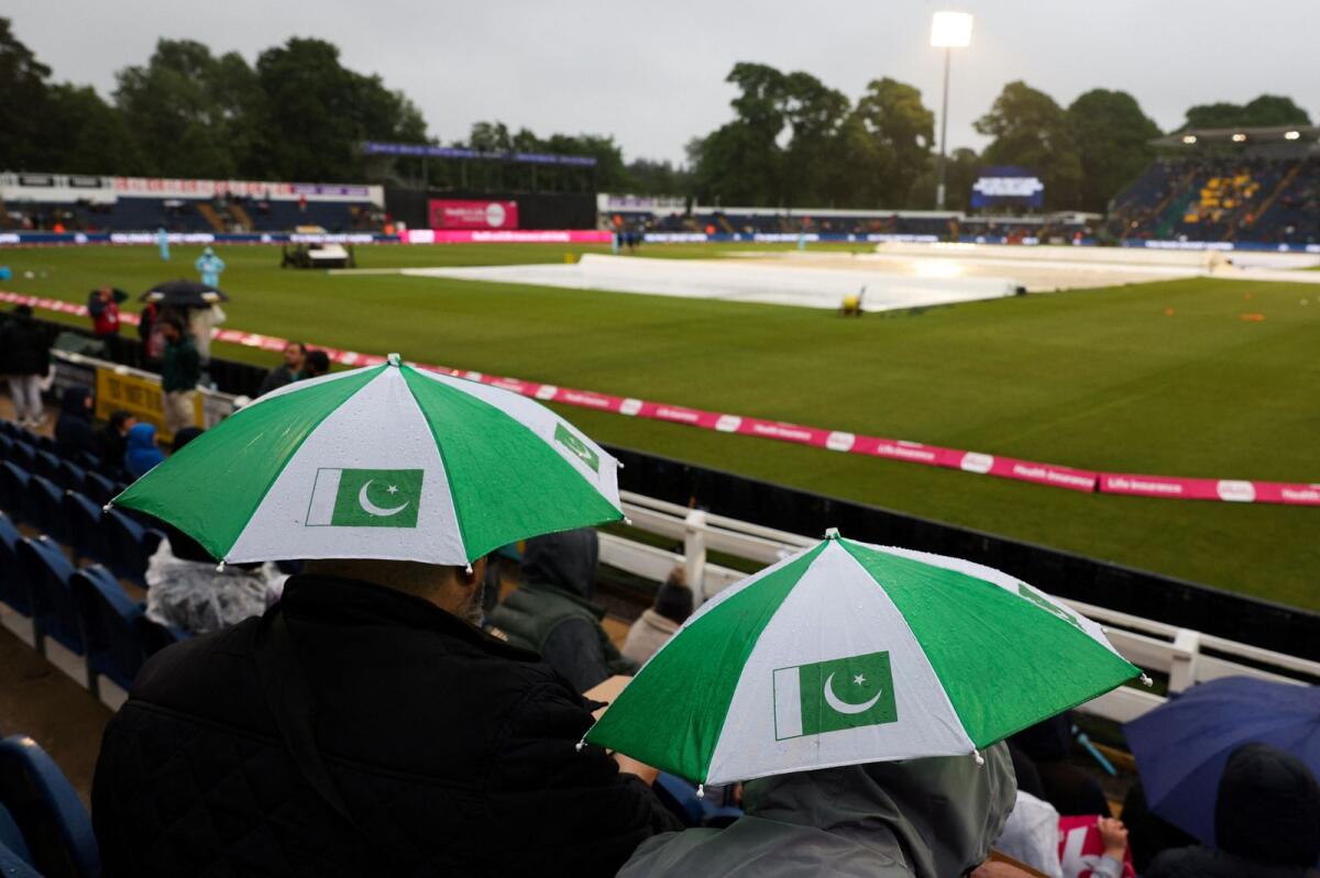 Supporters sit under their umbrella in the stands. — AFP