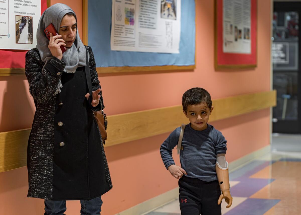 Accompanied by his aunt, Maha Abu Kuwaik, 4-year-old Omar Abu Kuwaik walks through a corridor at Shriners Children's Hospital with his new prosthetic arm on Wednesday, Feb. 28, 2024, in Philadelphia. — AP