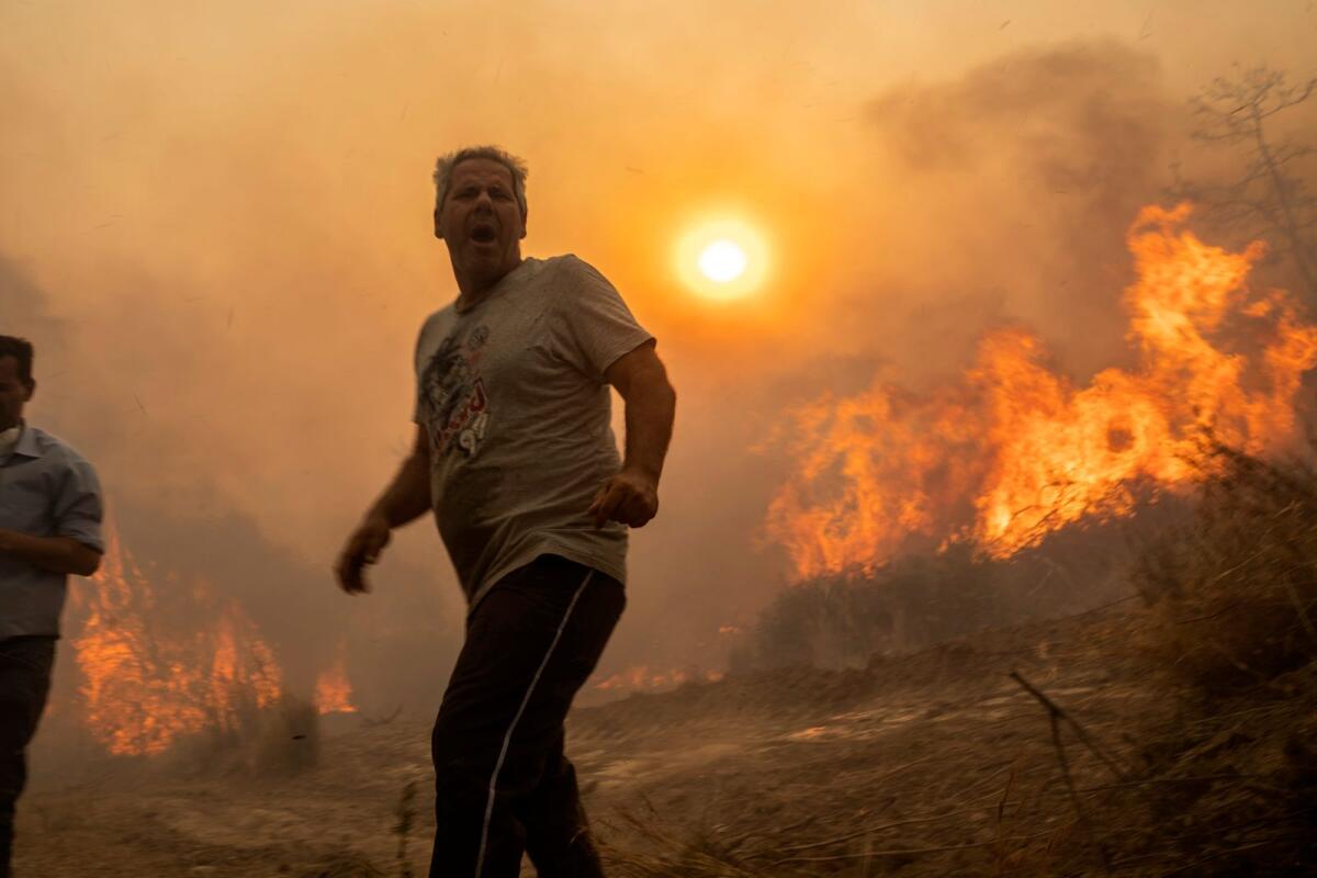 A local reacts as the flames burn trees in Gennadi village, on the Aegean Sea island of Rhodes, southeastern Greece, on Tuesday, July 25, 2023.Photo: AP