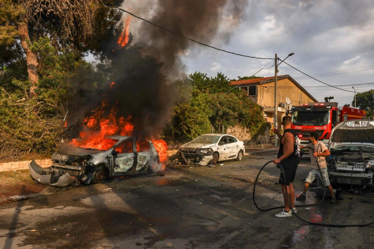 People douse a car blaze in the southern Israeli city of Ashkelon after a rocket attack from Gaza on October 9, 2023. Photo: AFP