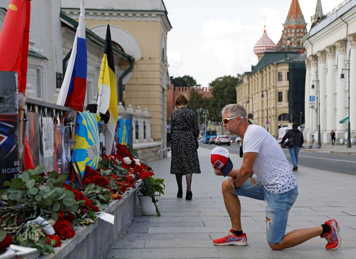 A man takes a knee in front of a makeshift memorial set up after the presumed death of Yevgeny Prigozhin in Moscow on Friday. — Reuters