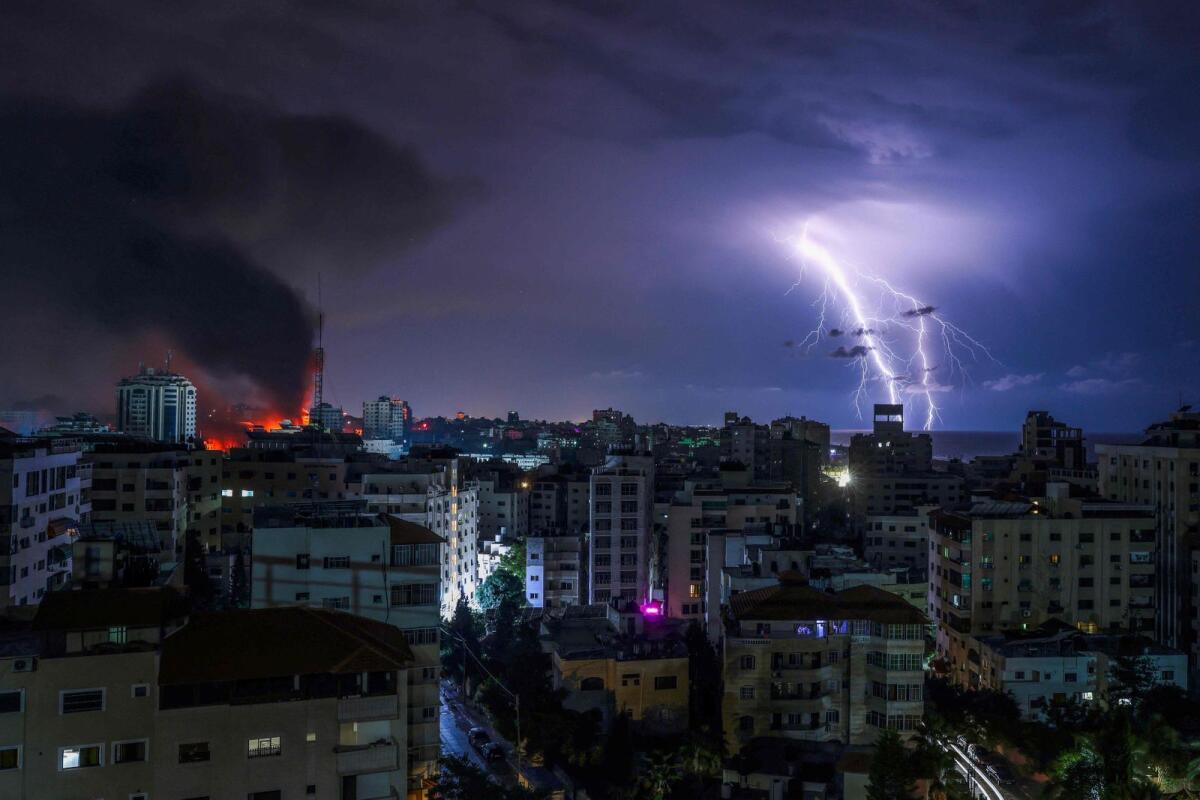 Lightning strikes as smoke billows following an Israeli airstrike in Gaza City on October 9, 2023. Photo: AFP
