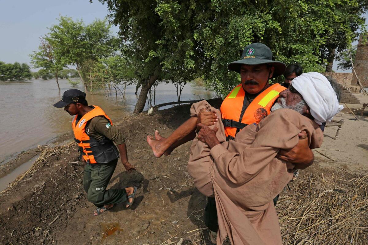 An elderly man is being evacuated by a rescue staff from a flooded area in Bahawalnagar of Punjab province on August 26, 2023. — AFP