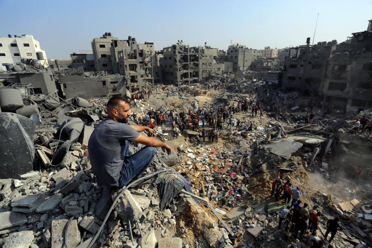 A man sits on the rubble as others wander among debris of buildings that were targeted by Israeli airstrikes in Jabaliya refugee camp, northern Gaza Strip on Nov. 1, 2023. Photo: AP