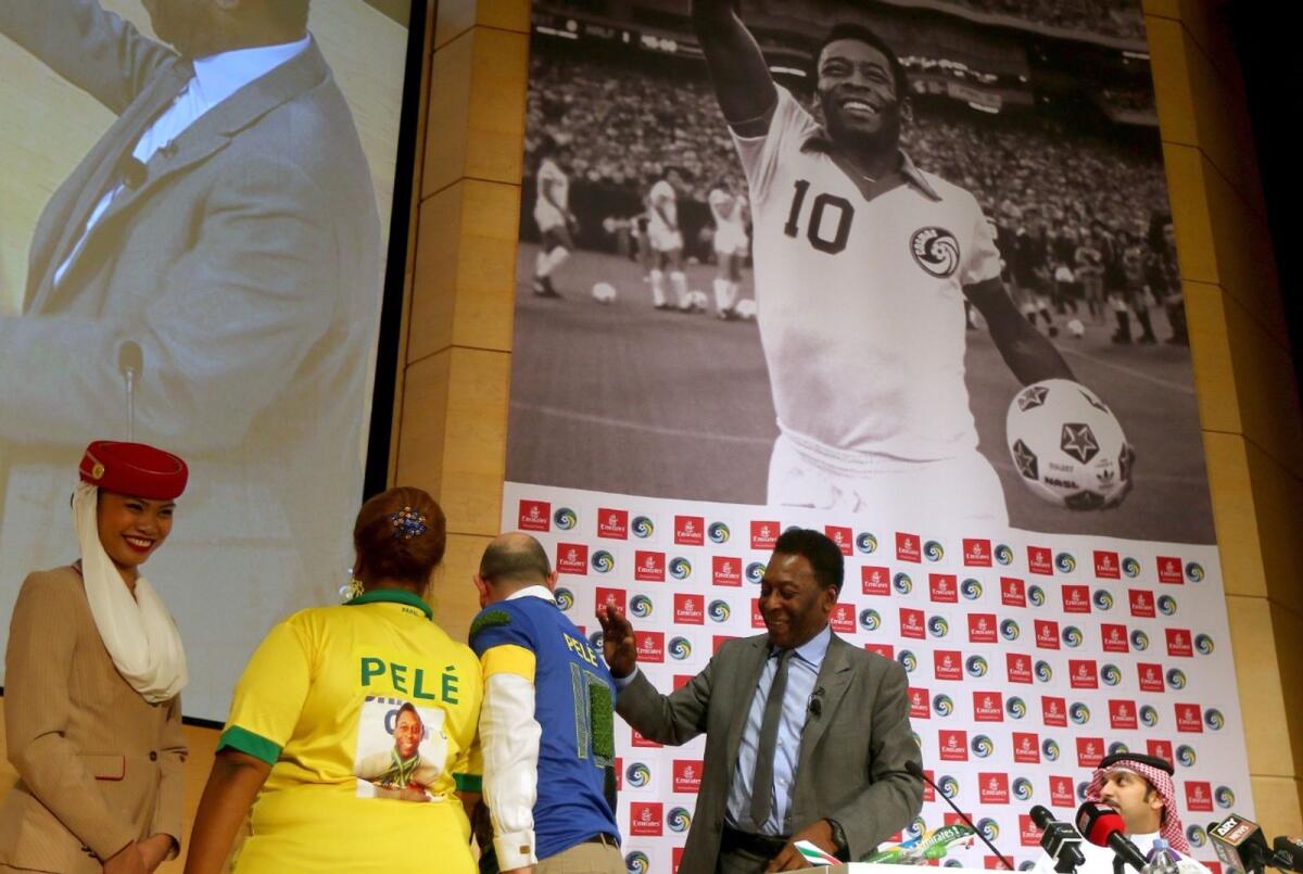 Pele looks at two fans wearing custom Pele T-shirts during a special screening of the iconic Brazilian player's greatest moments at his Dubai headquarters in 2014. - AFP file