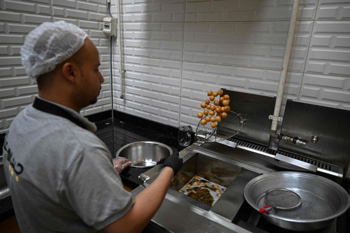 An employee fries sweet pastry with traditional Sudanese taste at a restaurant run by a businessman who relocated to Cairo after fleeing the ongoing war in Sudan, on May 27, 2024. — AFP