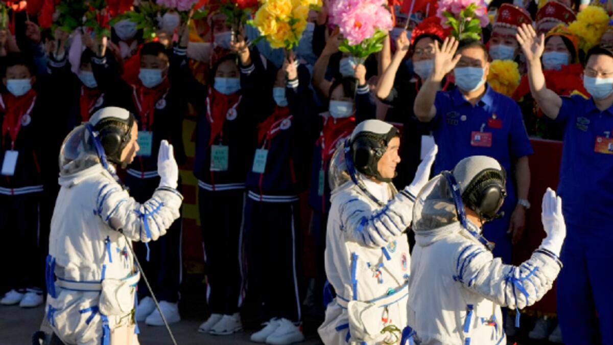 Chinese astronauts wave as they prepare to board for lift-off at the Jiuquan Satellite Launch Center in Jiuquan in northwestern China on June 17. AP