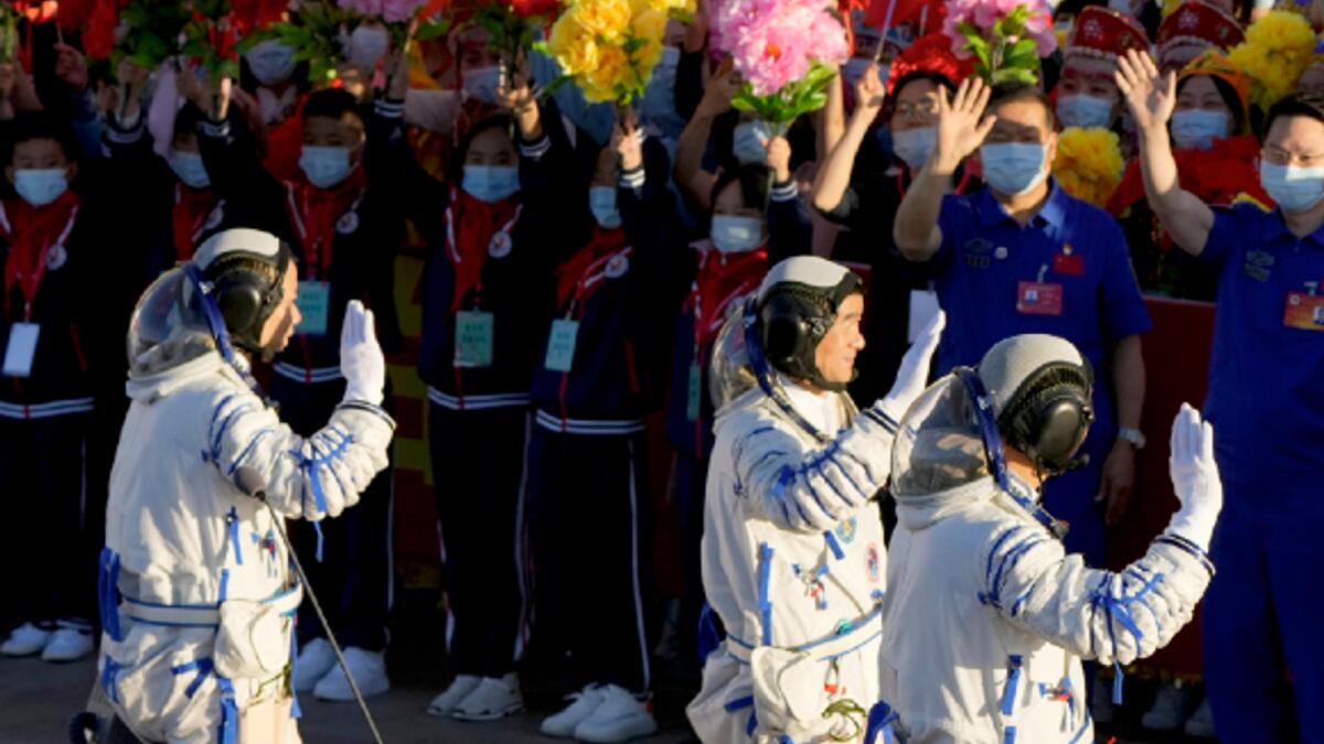 Chinese astronauts wave as they prepare to board for lift-off at the Jiuquan Satellite Launch Center in Jiuquan in northwestern China on June 17. AP