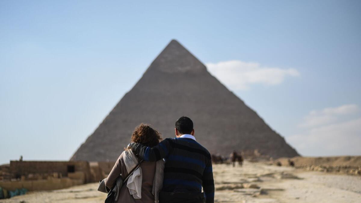 A couple look at one of the Giza pyramids in the southern Cairo Giza district on January 20, 2016.  Since Egypt's then army chief and now President Abdel Fattah al-Sisi ousted Islamist leader Mohamed Morsi in 2013, a deadly insurgency led by the Islamic State jihadist group has kept away millions of tourists.- TO GO WITH AFP STORY BY JAY DESHMUKH/ AFP / MOHAMED EL-SHAHED / TO GO WITH AFP STORY BY JAY DESHMUKH