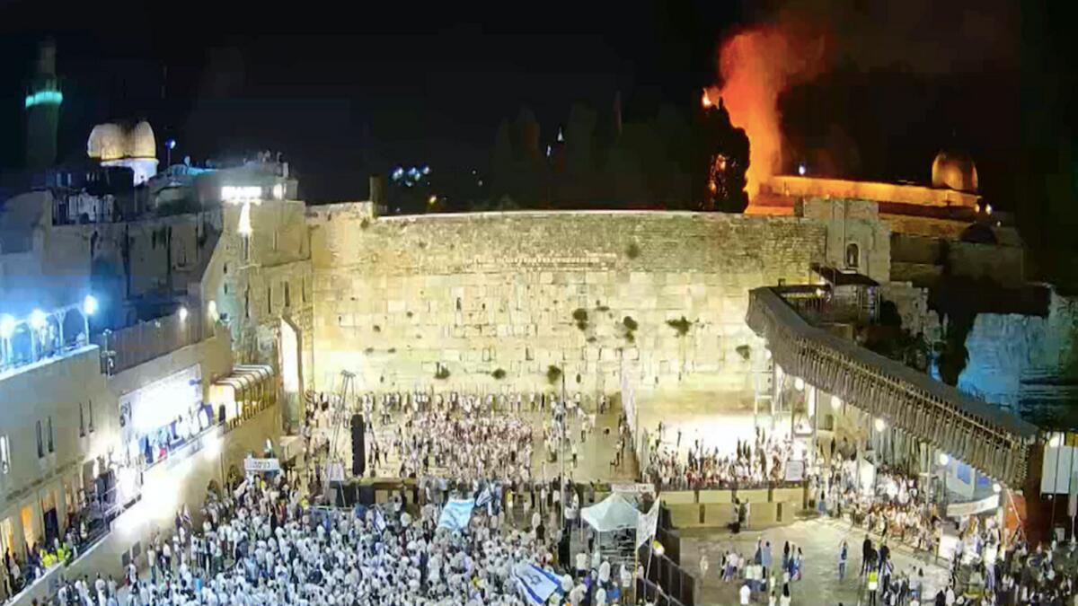 Israelis gather at the Western Wall as a blaze is seen in the background at the compound that houses Al Aqsa mosque.