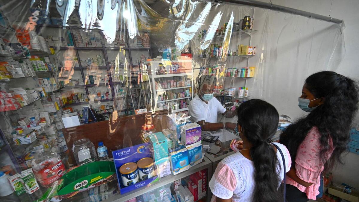 A pharmacist attends to his customers at a local drug store in Colombo. — AFP file photo