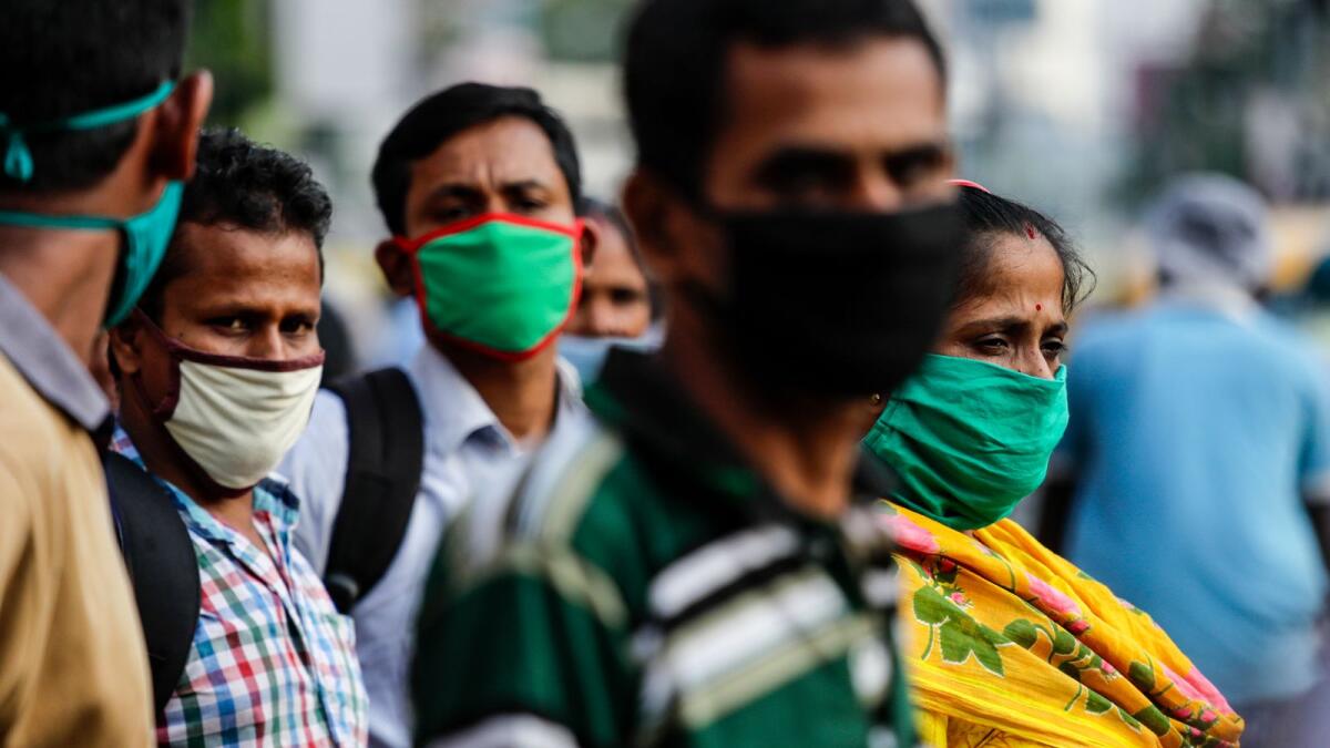 Commuters with face mask to prevent spreading coronavirus wait for but to travel to their destination in Kolkata, India. AP