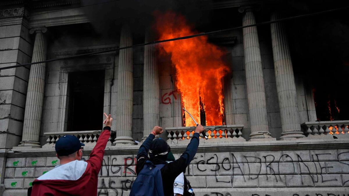 Demonstrators gesture after setting on fire an office of the Congress building during a protest demanding the resignation of President Alejandro Giammattei, in Guatemala City.