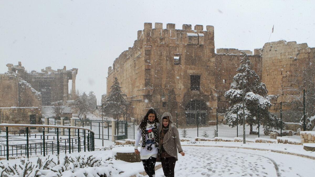 Women walk in snow at the historical ruins of Baalbek in eastern Lebanon, January 25, 2016. Reuters