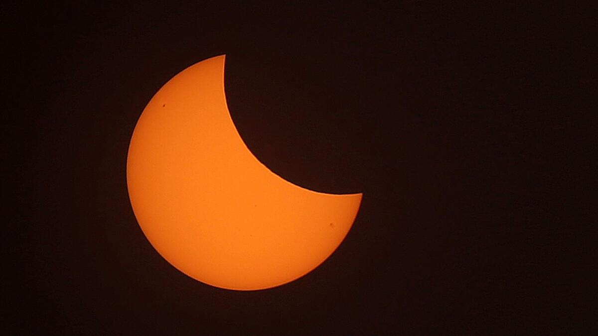 A brilliantly orange crescent hangs low in the sky in Kuwait City. (AFP)