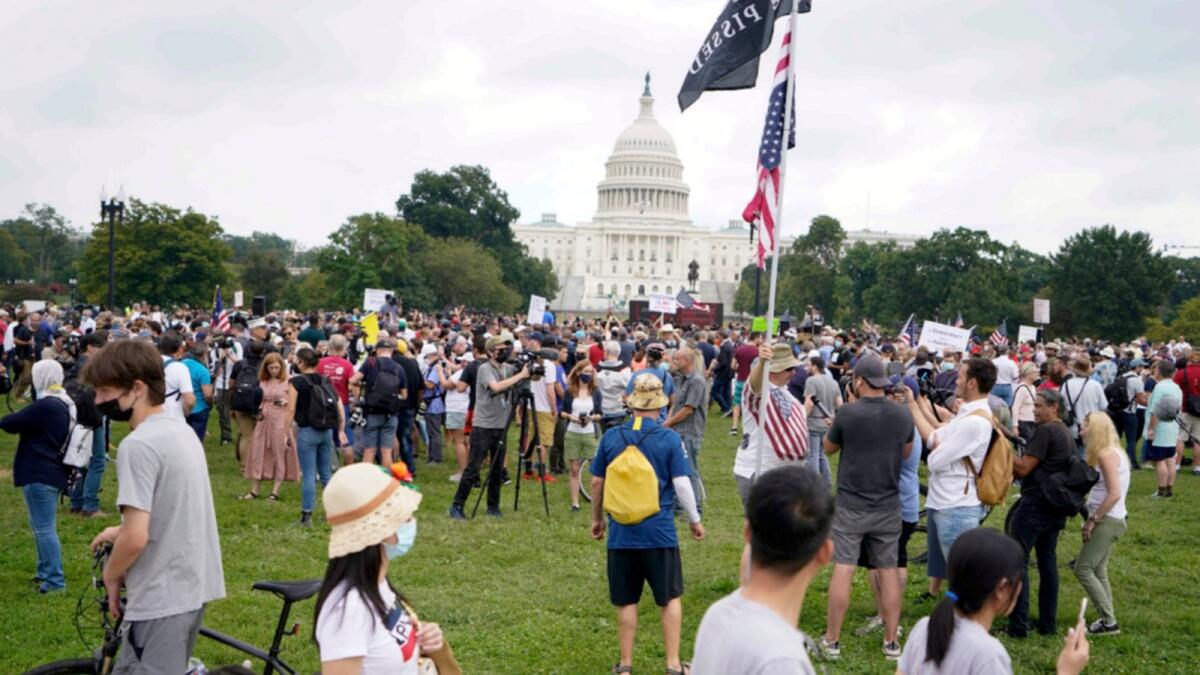 People walk by as others attend a rally near the US Capitol in Washington. — AP