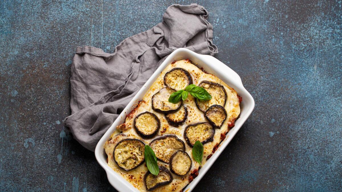 Greek mediterranean dish Moussaka with baked eggplants, ground beef in white ceramic casserole on rustic stone background from above, traditional dish of Greece.