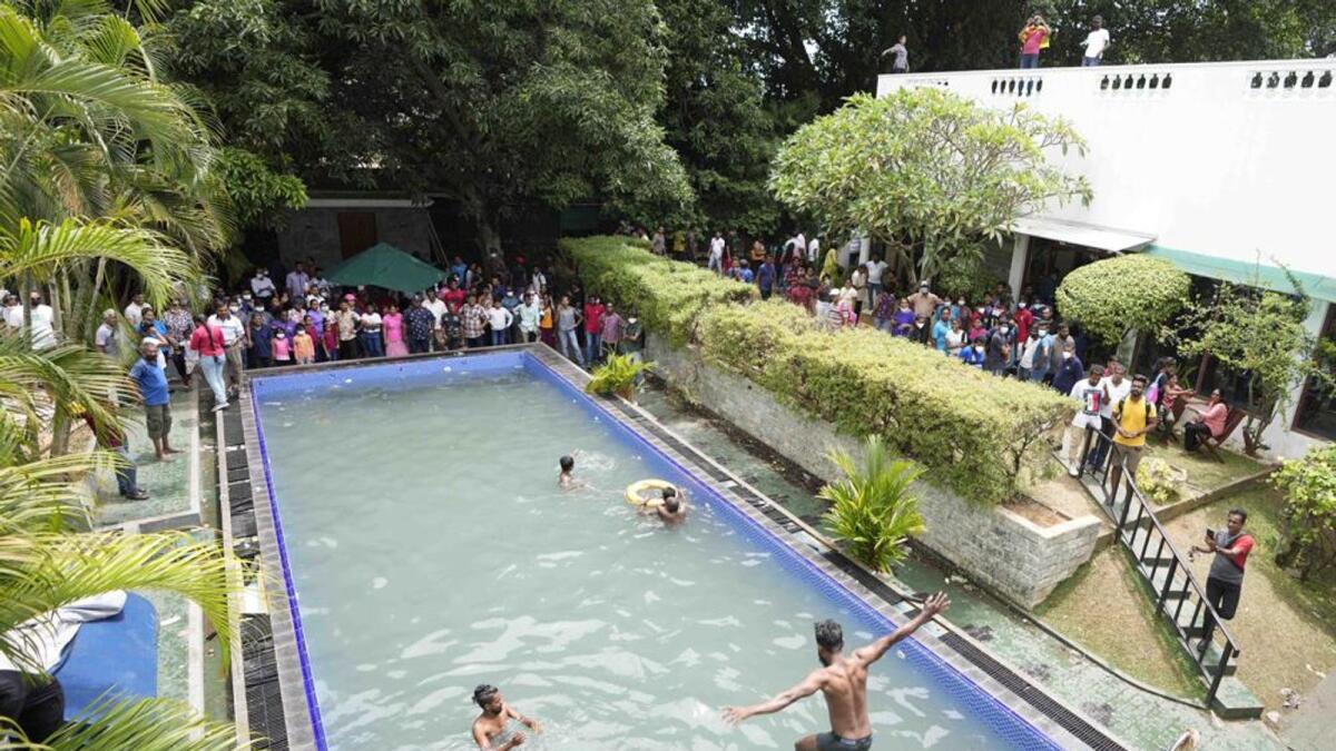 Protesters swim as onlookers wait at a swimming pool in the President's official residence