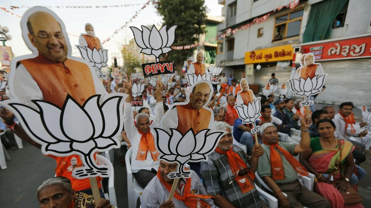 Supporters of Indias ruling Bharatiya Janata Party (BJP) hold cutouts of party president Amit Shah with the party symbol during a public rally in Ahmadabad, India.-AP