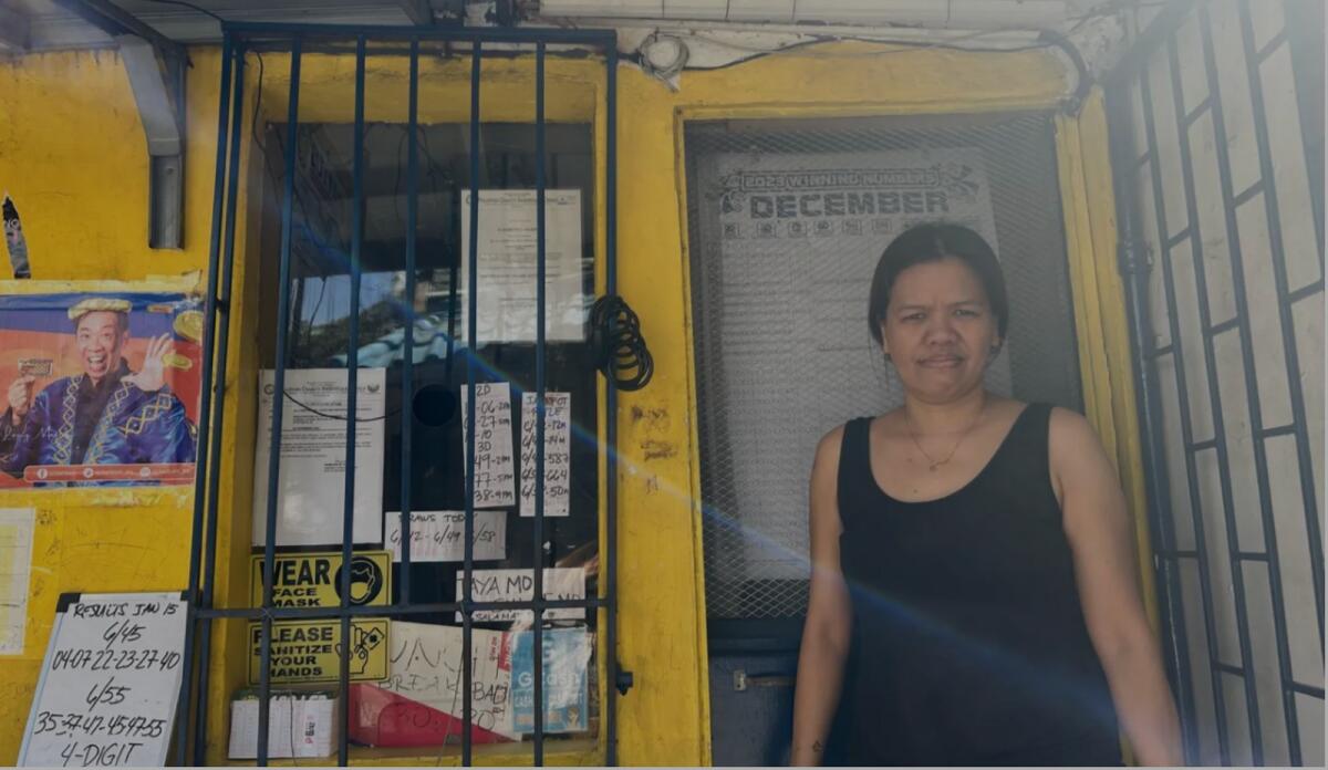 Lucy Ortega stands in front of a lottery outlet where she works part time in Manila on January 16, 2024. — Reuters