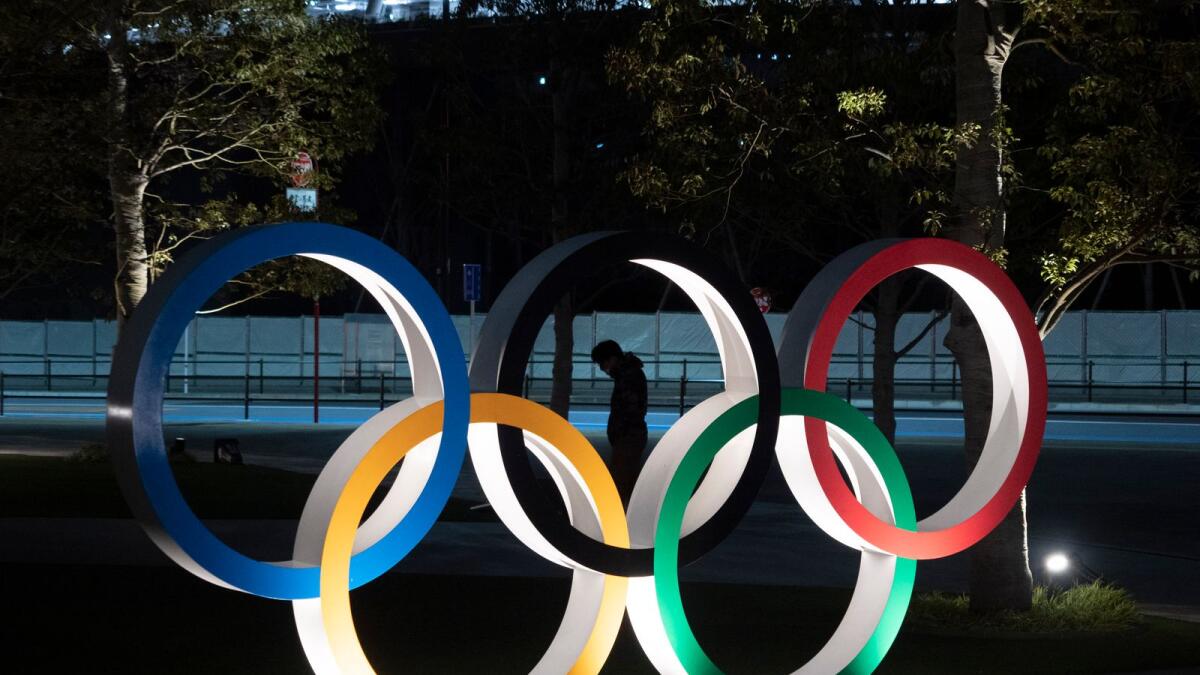 A man is seen through the Olympic rings in front of the New National Stadium in Tokyo. — AP