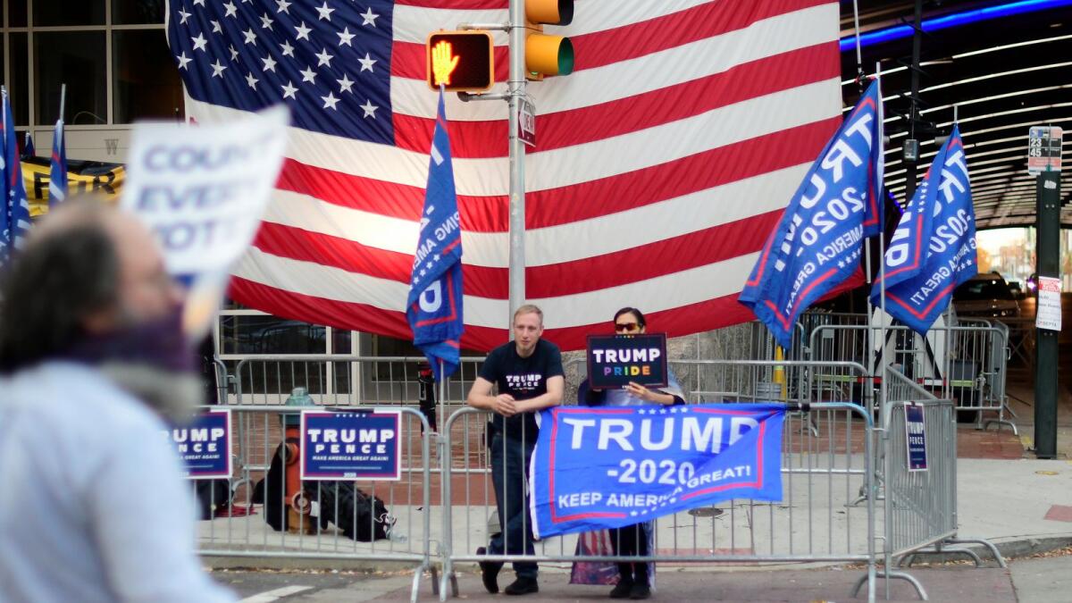 Supporters of U.S. President Donald Trump rally in front of a large U.S. flag, outside the Pennsylvania Convention Center.