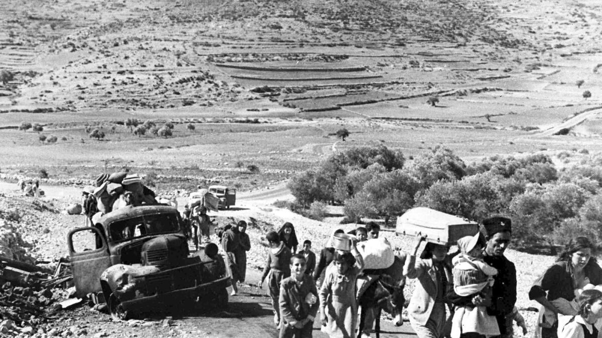 A group of Arab refugees walks along a road from Jerusalem to Lebanon, carrying their belongings with them on November 9, 1948. — AP file