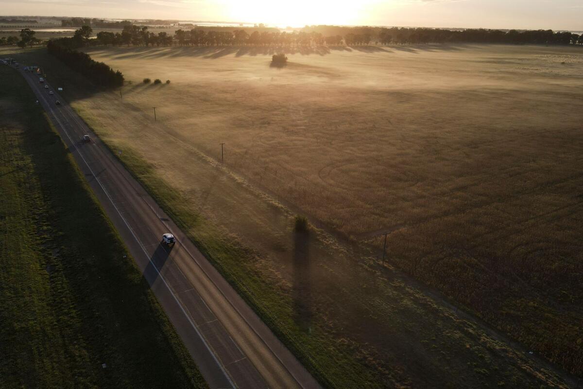 A car drives down a road near farmland in Lobos, Argentina, on April 14, 2023. Huge amount of the harvest of soybean and corn has been lost in Argentina due to drought. — AP
