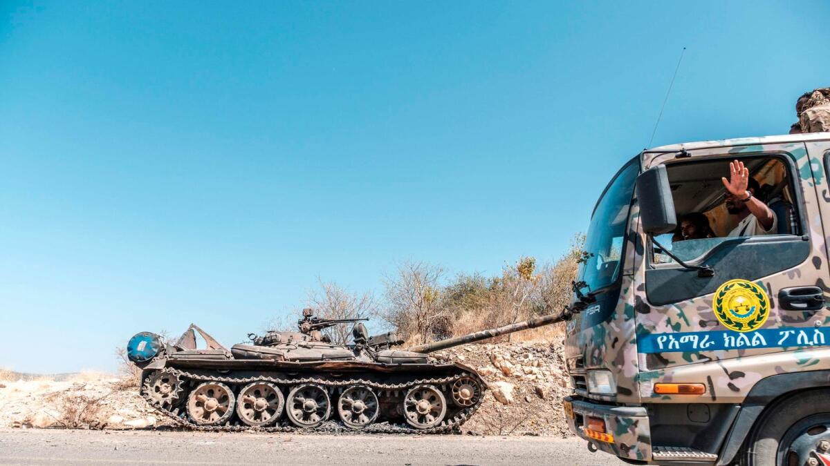 A damaged tank stands abandoned on a road as a truck of the Amhara Special Forces passes by near Humera, Ethiopia, on Sunday.