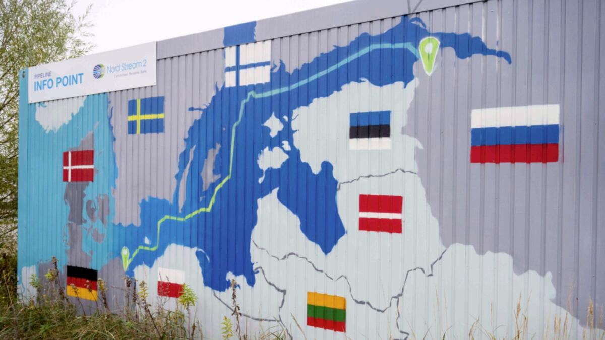 A sign reading 'Nord Stream 2 Committed. Reliable. Safe.' hangs above a painted map of the Nord Stream 2 pipeline from Russia to Germany at the natural gas receiving station in the Lubmin industrial estate in Lubmin, Germany. — AP file