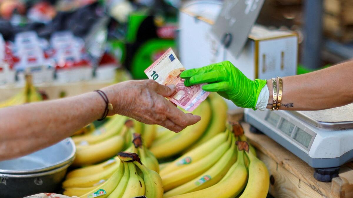 A shopper pays with a ten Euro bank note at a local market in Nice, France. — Reuters