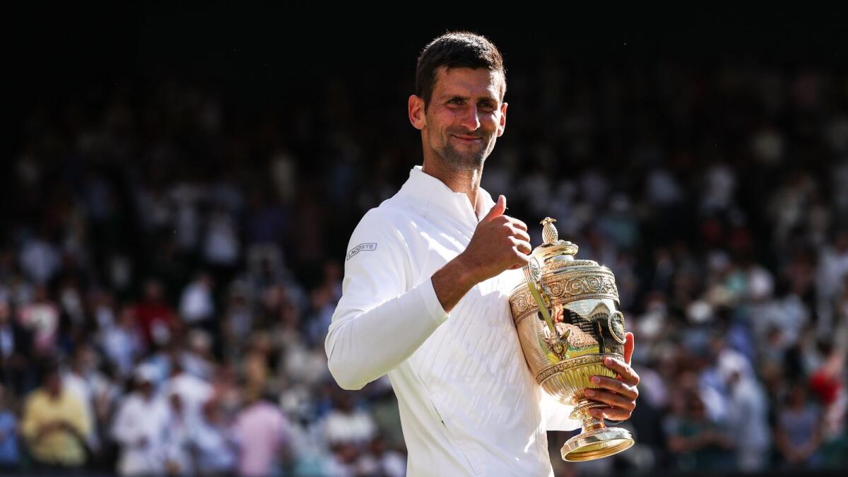 Novak Djokovic smiles as he holds the trophy after defeating Nick Kyrgios in the Wimbledon final. (AFP)